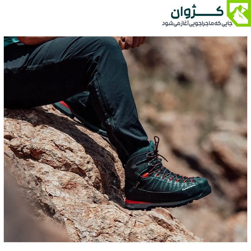 نمای نیم‌رخ از کفش قرمز S2 قارتال در پای فردی نشسته در طبیعت