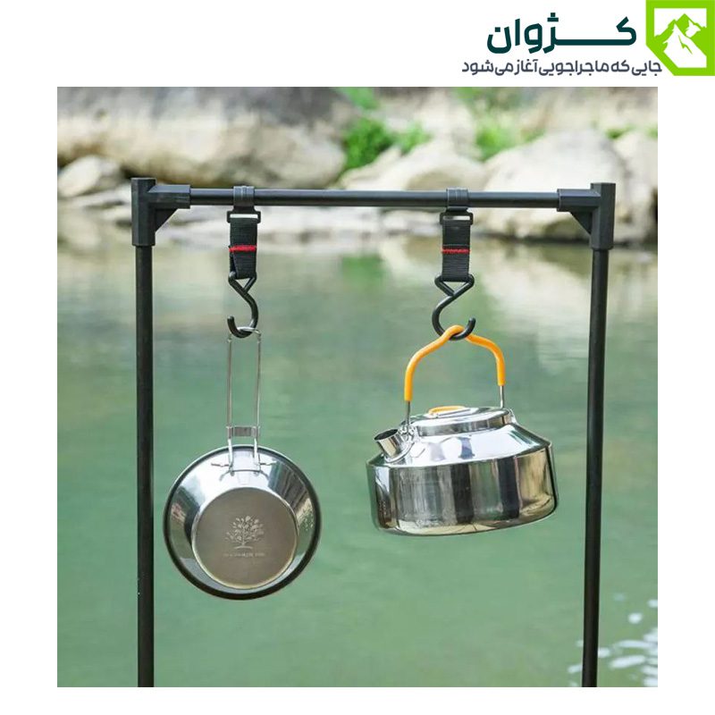 کتری استیل 0.9 لیتری آویزان در فضای باز، در کنار وسیله‌ای دیگر، با پس‌زمینه‌ای از رودخانه و آب جاری.