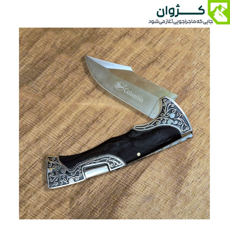 چاقوی کلمبیا مدل A3157-1 در حالت نیمه‌باز، روی سطح چوبی قرار گرفته؛ زاویه باز شدن تیغه، مکانیزم قفل و جزئیات دسته به‌خوبی قابل مشاهده‌اند.