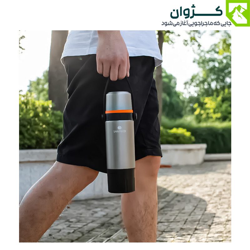 فلاسک دوجداره سانتکو مدل KAFE در دست فردی در فضای باز، نمای نزدیک از بدنه استیل نقره‌ای با دسته سیلیکونی