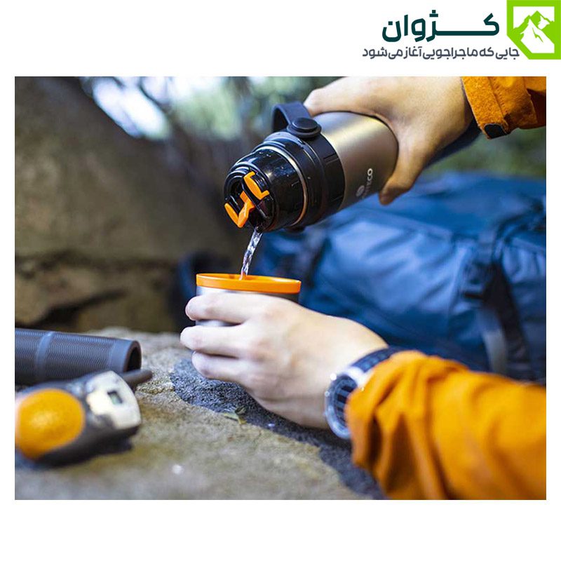 فلاسک نقره‌ای در دست طبیعت‌گرد در حال ریختن مایعات