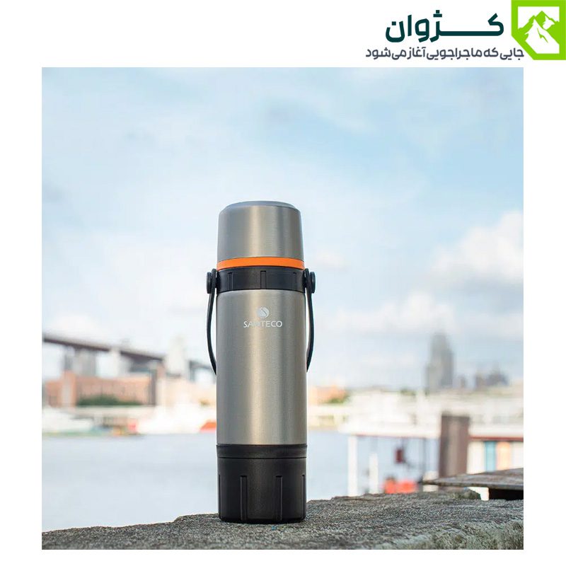 فلاسک نقره‌ای ایستاده روی سنگ با نمای دریا و پل