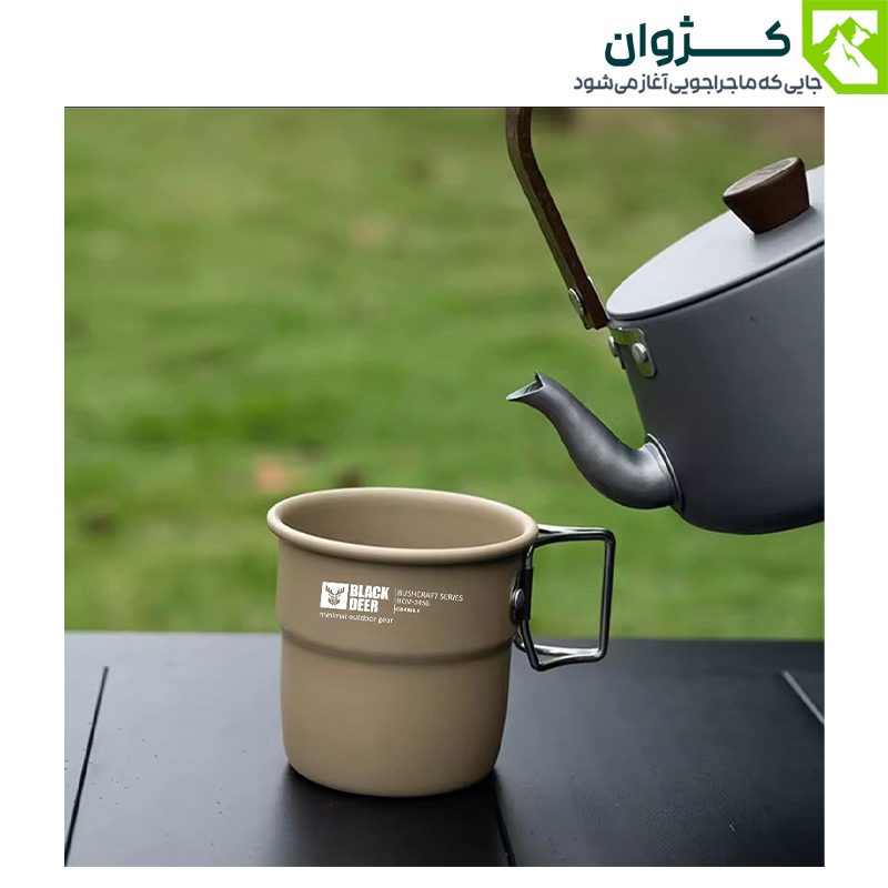 لیوان کمپینگ بلک‌دیر – رنگ خاکی، روی میز مشکی در طبیعت، نمایش هماهنگی با محیط و طراحی مقاوم