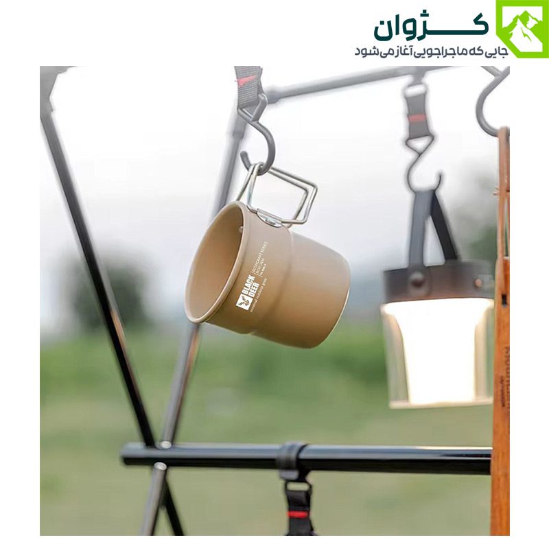 لیوان کمپینگ بلک‌دیر – رنگ خاکی، آویزان در فضای جنگلی، ساخته‌شده از آلیاژ آلومینیوم و استیل تصفیه‌شده 304