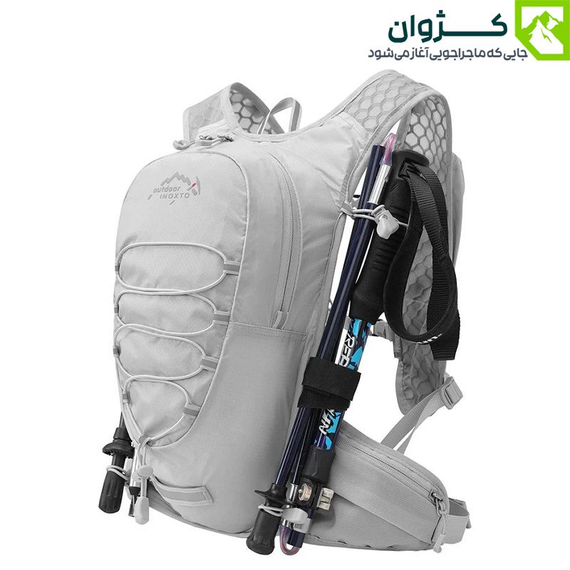 کوله رانینگ INOXTO مدل 577 در رنگ خاکستری روشن، قرار گرفته در محیط کوهستانی، دارای بند نگه‌دارنده باتوم، بندهای قابل تنظیم و طراحی ارگونومیک، مناسب برای طبیعت‌گردی سبک و کوهنوردی یک‌روزه