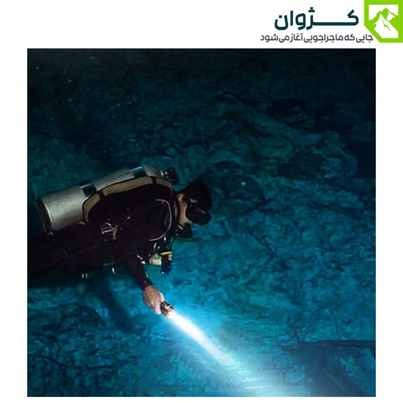 غواص مجهز به چراغ قوه SD-Q35 در حال کاوش در محیط زیر آب با پس‌زمینه صخره‌ای و نورپردازی در عمق دریا، نماد ماجراجویی و اکتشاف