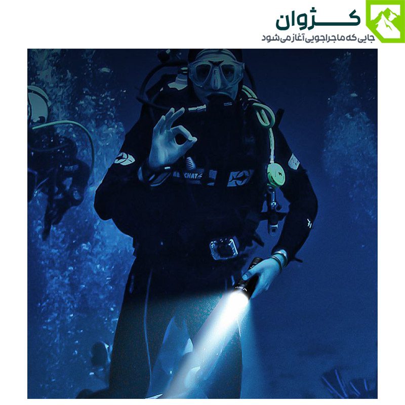 غواص مجهز به چراغ قوه SD-Q35 در اعماق آب، در حال ارسال علامت OK، با پس‌زمینه آبی و سایر غواصان در محیط زیر آب